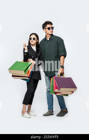 Une paire d'hommes et de femmes portaient des lunettes et transportaient beaucoup de sacs en papier pour faire du shopping. Banque D'Images