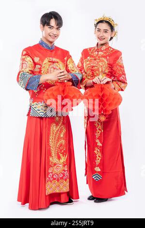 Hommes et femmes portant qipao debout avec lampe nid d'abeille, isolé sur fond blanc. Banque D'Images