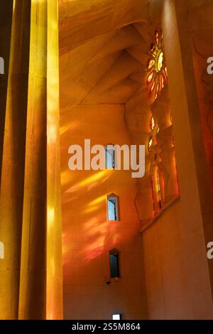 Le soleil de l'après-midi filtre à travers les vitraux de la Sagrada Familia, projetant des teintes vibrantes d'orange et de jaune, créant un affichage époustouflant Banque D'Images