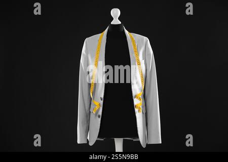 Mannequin féminin avec veste grise et ruban à mesurer sur fond sombre Banque D'Images