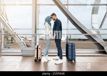 Portrait d'un couple islamique aimant qui colle à l'aéroport tout en attendant le vol Banque D'Images