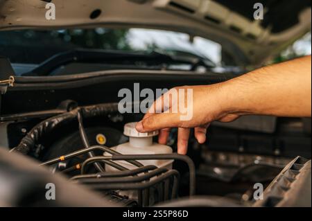 Un homme ouvre le capot d'une voiture pour réparer la voiture en raison d'une panne. Banque D'Images