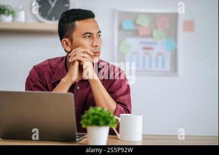 Un homme travaille dans un bureau et pense à fixer des tâches. Banque D'Images