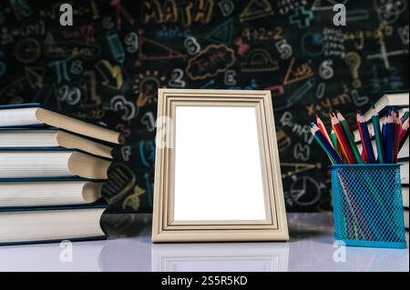 cadre photo blanc, livre et crayons de couleur dans la salle de classe Banque D'Images