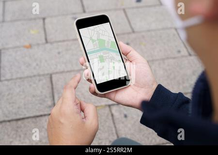 Femme avec des bagages dans la rue du centre-ville de recherche d'emplacement dans l'application de carte en ligne sur téléphone intelligent en utilisant la navigation GPS Banque D'Images