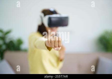 Jeune joueur de femme asiatique portant la réalité virtuelle touchant l'air pendant l'expérience VR future Home Technology Player hobby concept de plaisir ludique Banque D'Images