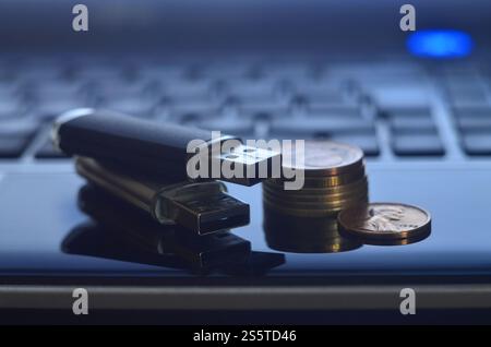 Cartes flash USB couchées sur le boîtier noir de l'ordinateur portable devant son clavier. Le concept de gagner sur Internet, monétisation en ligne et paiement de Banque D'Images