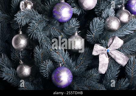Photo détaillée du sapin de Noël décoré de cadeaux, de jouets sphériques de couleur vive, de rubans et de guirlandes en gros plan. Arrière-plan abstrait pour Banque D'Images
