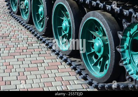 Un véhicule militaire sur chenilles se tient sur un carré de pavés. Photo de chenilles vertes avec des roues en métal que les faire tourner Banque D'Images