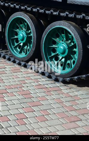 Un véhicule militaire sur chenilles se tient sur un carré de pavés. Photo de chenilles vertes avec des roues en métal que les faire tourner Banque D'Images