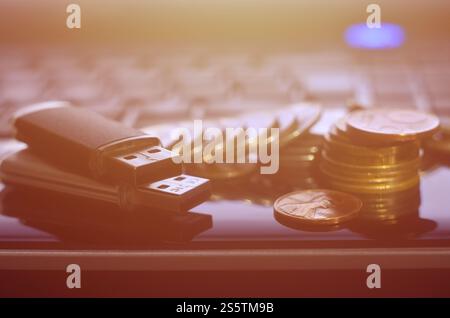 Cartes flash USB couchées sur le boîtier noir de l'ordinateur portable devant son clavier. Le concept de gagner sur Internet, monétisation en ligne et paiement de Banque D'Images