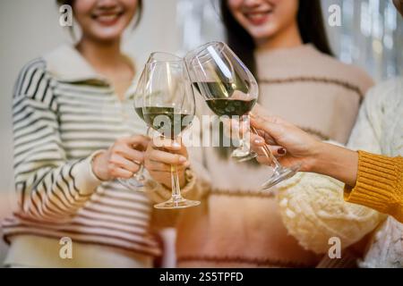 Amis joyeux appréciant la fête d'anniversaire à la maison. Amis asiatiques acclamant boire du vin rouge pour célébrer Noël ou la fête du nouvel an. Banque D'Images