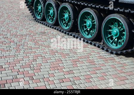 Un véhicule militaire sur chenilles se tient sur un carré de pavés. Photo de chenilles vertes avec des roues en métal que les faire tourner Banque D'Images