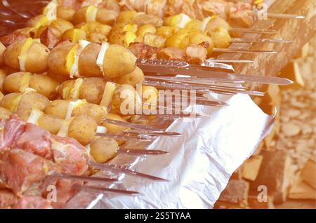 La viande et les pommes de terre sont plantées sur des brochettes de métal. Le processus de la cuisson des brochettes shish. La nourriture du camp russe et ukrainien Banque D'Images