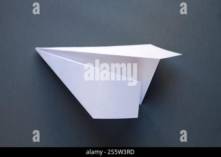 Origami avion en papier blanc isolé sur un fond gris vierge. Origami avion en papier blanc isolé sur un fond gris Banque D'Images