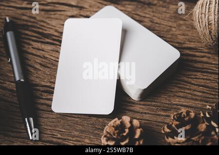 Des cartes vides, des stylos et des pommes de pin séchées sont placés sur le bois. Banque D'Images