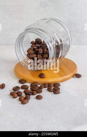 Top prendre des grains de café dans une tasse en verre sur une base en bois sur fond blanc isolé Banque D'Images