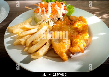 Une assiette de frites frites, de poisson frit à la farine et de légumes hachés servis comme repas du midi dans un restaurant Banque D'Images