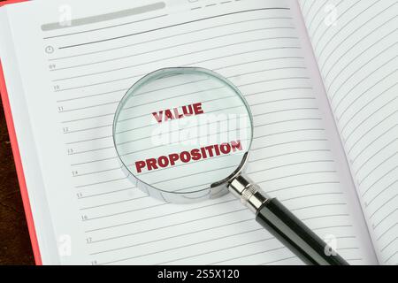 Concept de valeur ajoutée. PROPOSITION DE VALEUR DE mots sur une page blanche d'un carnet d'affaires à travers une loupe. Banque D'Images