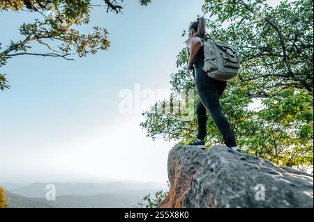 Vue arrière de jeune femme asiatique de randonnée debout au point de vue et regardant une belle vue avec heureux sur la montagne de pic et le soleil, espace de copie Banque D'Images