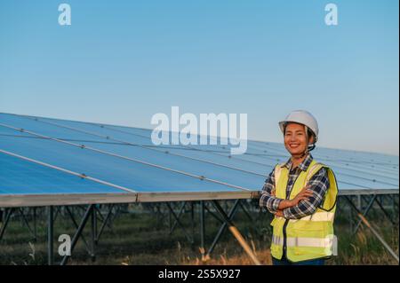 Portrait asiatique jeune belle femme dans un casque de protection. Ingénieur féminin avec détermination au panneau solaire à l'extérieur. croiser les bras et regarder Banque D'Images