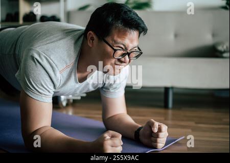 Homme drôle en surpoids dans les lunettes essayer de planquer sur le sol faire de l'entraînement, copier l'espace Banque D'Images
