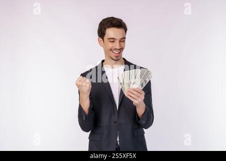 Portrait d'un homme joyeux tenant des billets d'un dollar et faisant un geste gagnant serrant le poing sur fond blanc. Finance, investissement et économies Banque D'Images