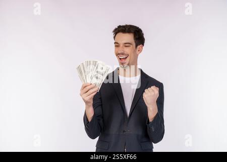Portrait d'un homme joyeux tenant des billets d'un dollar et faisant un geste gagnant serrant le poing sur fond blanc. Finance, investissement et économies Banque D'Images