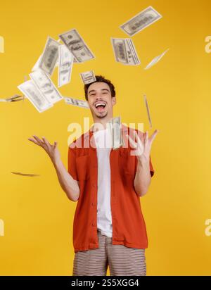 Portrait de jeune homme heureux jetant de l'argent tout en se tenant sur fond isolé. Concept d'argent et de richesse. Banque D'Images Portrait de jeune homme heureux jetant de l'argent tout en se tenant sur fond isolé. Concept d'argent et de richesse. Banque D'Images