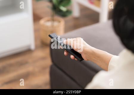 Femme âgée regardant la télévision intelligente et utilisant la télécommande main tenant la télévision audio télécommande Moyen âge asiatique film série de télévision Banque D'Images