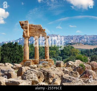 Temple de Dioscuri (Castor et Pollux) avec la ville d'Agrigente en arrière-plan. Ruines antiques célèbres dans la vallée des temples, Agrigente, Sicile, Italie. Banque D'Images