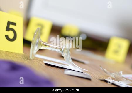 Verre brisé et bouteille de vin marqués comme preuve lors de l'enquête sur les lieux du crime. De nombreux marqueurs jaunes avec des chiffres se rapprochent. Verre brisé et Banque D'Images