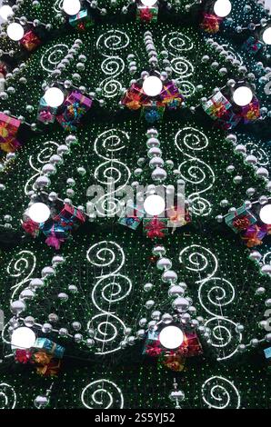 Un fragment d'un immense arbre de Noël avec de nombreux cadeaux, décorations et lumineux des lampes. Photo d'un arbre de Noël décoré close-up Banque D'Images