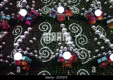 Un fragment d'un immense arbre de Noël avec de nombreux cadeaux, décorations et lumineux des lampes. Photo d'un arbre de Noël décoré close-up Banque D'Images