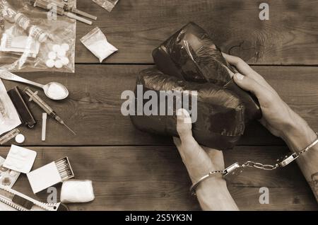 Trafiquant de drogue arrêté avec leurs paquets d'héroïne. La police arrête le trafiquant de drogue avec des menottes et beaucoup de stupéfiants sur la table en bois. 26 juin Banque D'Images