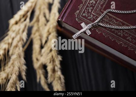Collier en argent avec croix crucifix sur livre biblique sacré chrétien sur table en bois noir. Demander des bénédictions de Dieu avec la puissance de la sainteté, qui Banque D'Images