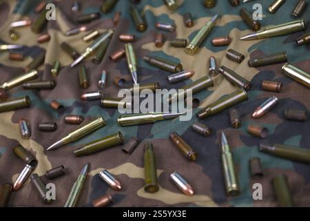 Beaucoup de balles de fusil et de cartouches sur fond de camouflage sombre. Concept d'action de guerre ou de chasse. Beaucoup de balles de fusil et de cartouches sur l'obscurité Banque D'Images