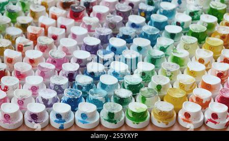 Un motif de nombreuses buses d'un pulvérisateur de peinture pour dessiner des graffitis, étalés en différentes couleurs. Les capuchons en plastique sont disposés en plusieurs rangées Banque D'Images