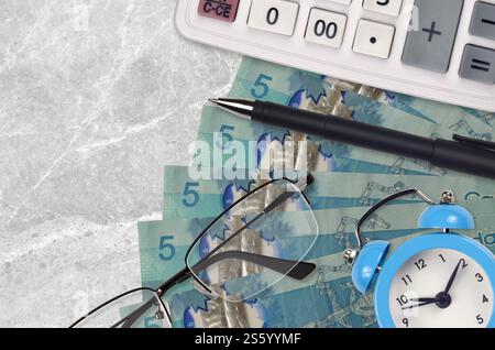 5 billets en dollars canadiens et calculatrice avec lunettes et stylo. Concept de prêt commercial ou de saison de paiement d'impôt. Planification financière et temps pour payer les impôts. Banque D'Images