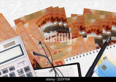 Billets de 50 dollars canadiens et calculatrice avec lunettes et stylo. Concept de saison de paiement d'impôt ou solutions d'investissement. Planification financière ou comptable Banque D'Images