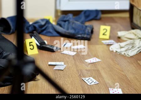 Enquête sur les lieux du crime - numérotation des preuves après le meurtre dans l'appartement. Beaucoup de cartes à jouer, portefeuille et vêtements avec des preuves Banque D'Images