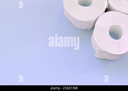 Concept de panique pandémique du coronavirus. Peu de nouveaux rouleaux de papier toilette sur fond bleu clair. Composition à plat minimaliste avec espace de copie Banque D'Images