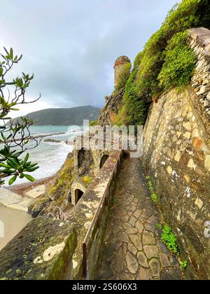 Vieille tour de pierre et chemin près de la mer en automne en Italie. Municipalité Moneglia, région Ligurie. Vue depuis la montagne. Banque D'Images