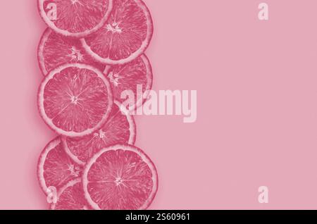 Vue de dessus des tranches de fruits de citron jaune sur fond de citron vert brillant. Une ligne verticale saturée d'agrumes avec espace de copie. Image minimaliste à plat teinte Banque D'Images