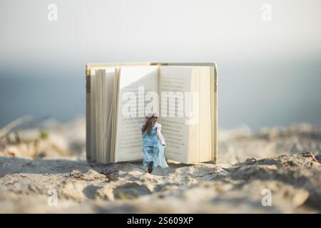 Femme avec une robe bleue et des cheveux flottant courir à l'intérieur d'un livre ouvert géant Banque D'Images