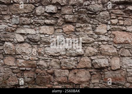 Texture d'un mur de pierre avec beaucoup de grosses pierres brunes et grises armées de ciment. Vieux château mur de pierre texture fond pour usage médiéval. Partie d'un Banque D'Images
