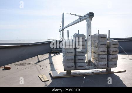 Contrepoids ou équilibrage de poids blocs de béton ou de briques faisant partie de la plate-forme suspendue de câble métallique pour les travaux de façade sur des bâtiments à plusieurs étages élevés. Banque D'Images