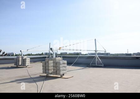 Contrepoids ou équilibrage de poids blocs de béton ou de briques faisant partie de la plate-forme suspendue de câble métallique pour les travaux de façade sur des bâtiments à plusieurs étages élevés. Banque D'Images