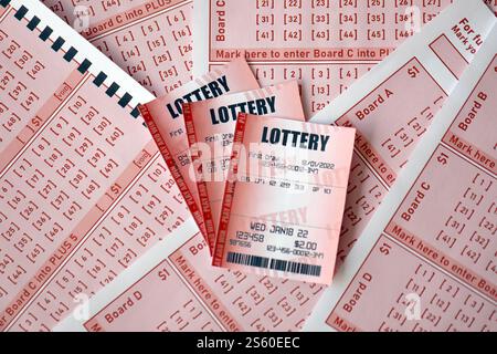 Billet de loterie rouge se trouve sur des feuilles de jeu roses avec des numéros pour marquer pour jouer à la loterie. Concept de jeu de loterie ou dépendance au jeu. Gros plan Banque D'Images