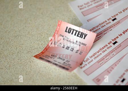 Billet de loterie rouge se trouve sur des feuilles de jeu roses avec des numéros pour marquer pour jouer à la loterie. Concept de jeu de loterie ou dépendance au jeu. Gros plan Banque D'Images